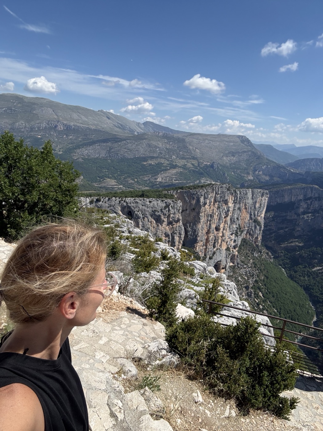 Kathrin im Profil an einem Aussichtspunkt über einer Felsschlucht, Berge im Hintergrund